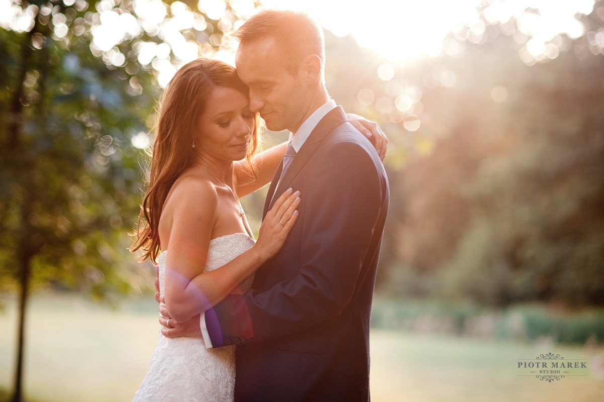 fotograf ślubny śląsk - Nowożeńcy obejmują się w promieniach słońca