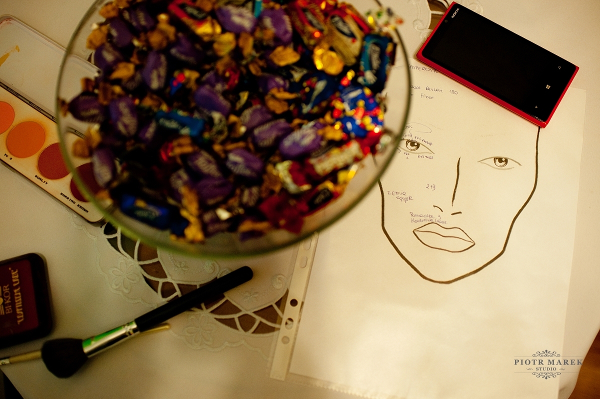 fotografia ślubna katowice - Na stole leży obrazek twarzy, miska z cukierkami oraz telefon