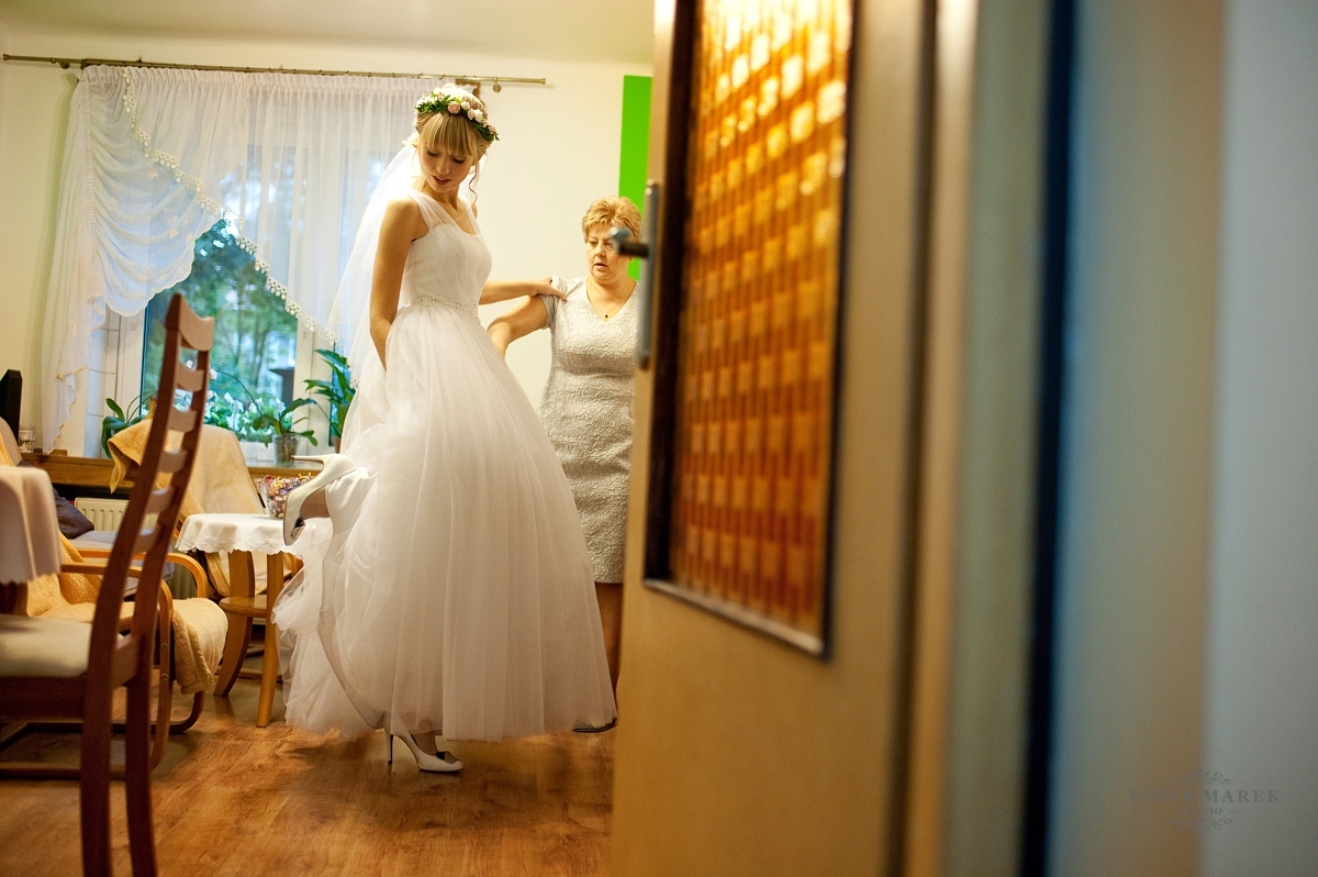fotografia ślubna gliwice - Pani młoda zakłada suknię i szpilki
