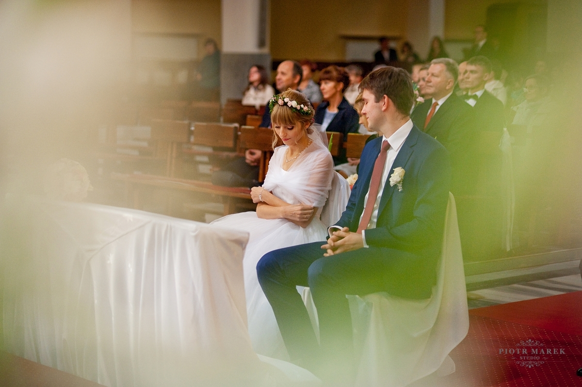 fotografia ślubna śląsk - Młoda para siedzi przed ołtarzem