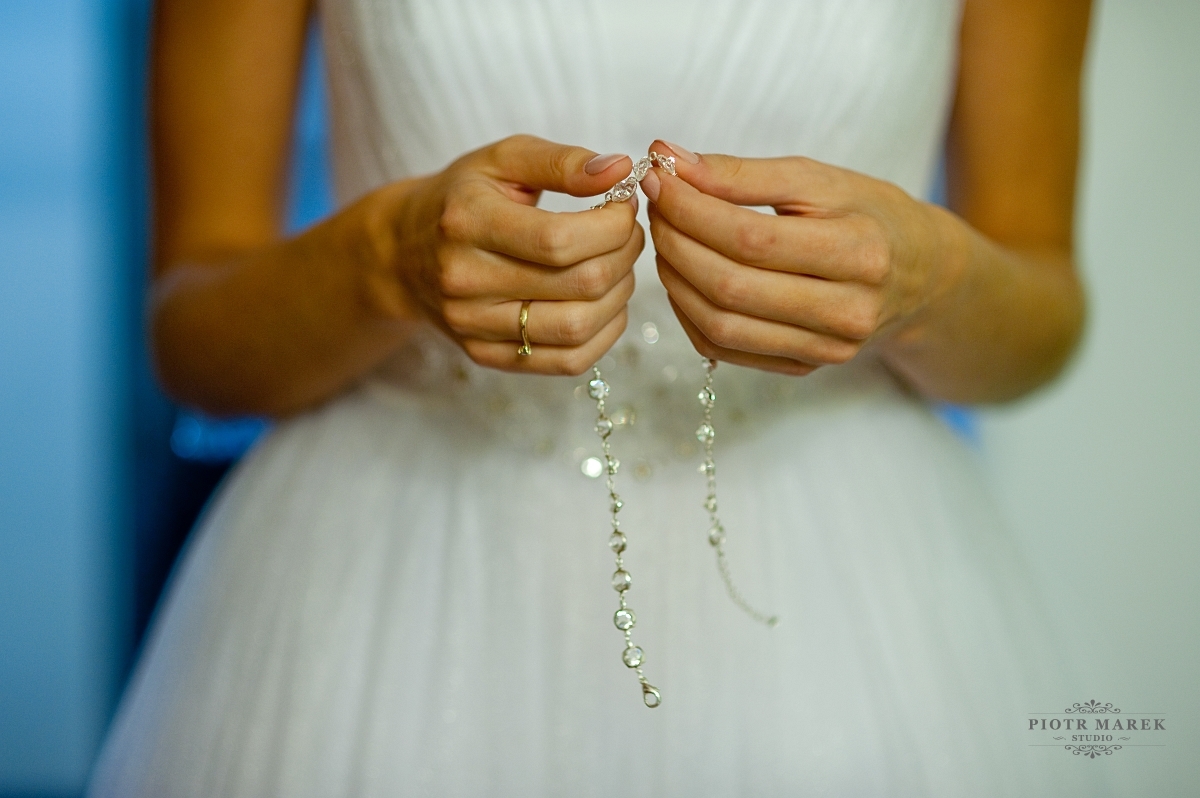 zdjęcia ślubne rybnik - Pani mloda trzyma w rękach naszyjnik