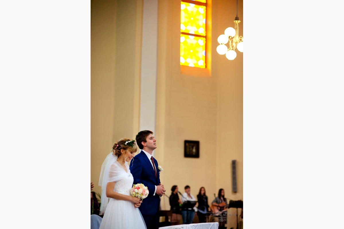 zdjęcia ślubne rybnik - Młoda para stoi przed ołtarzem