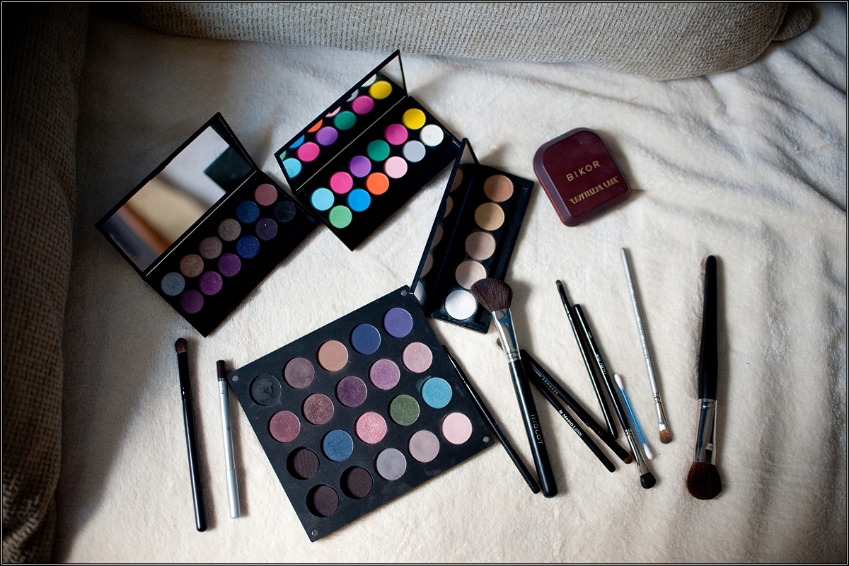 fotografia ślubna katowice - Palety cieni do powiek w rozmaitych odcieniach barw. Obok nich znajdują się pędzle do makijażu.