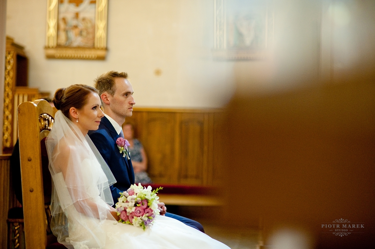 fotograf ślubny rybnik - Młoda para siedzi przed ołtarzem
